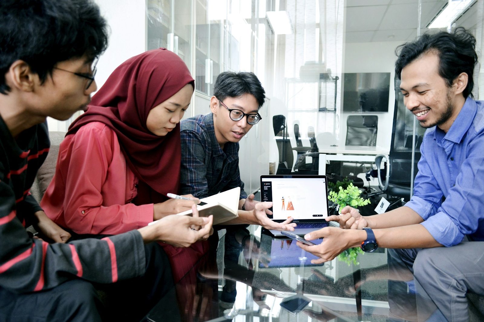 Tim kantor Indonesia berdiskusi di depan laptop