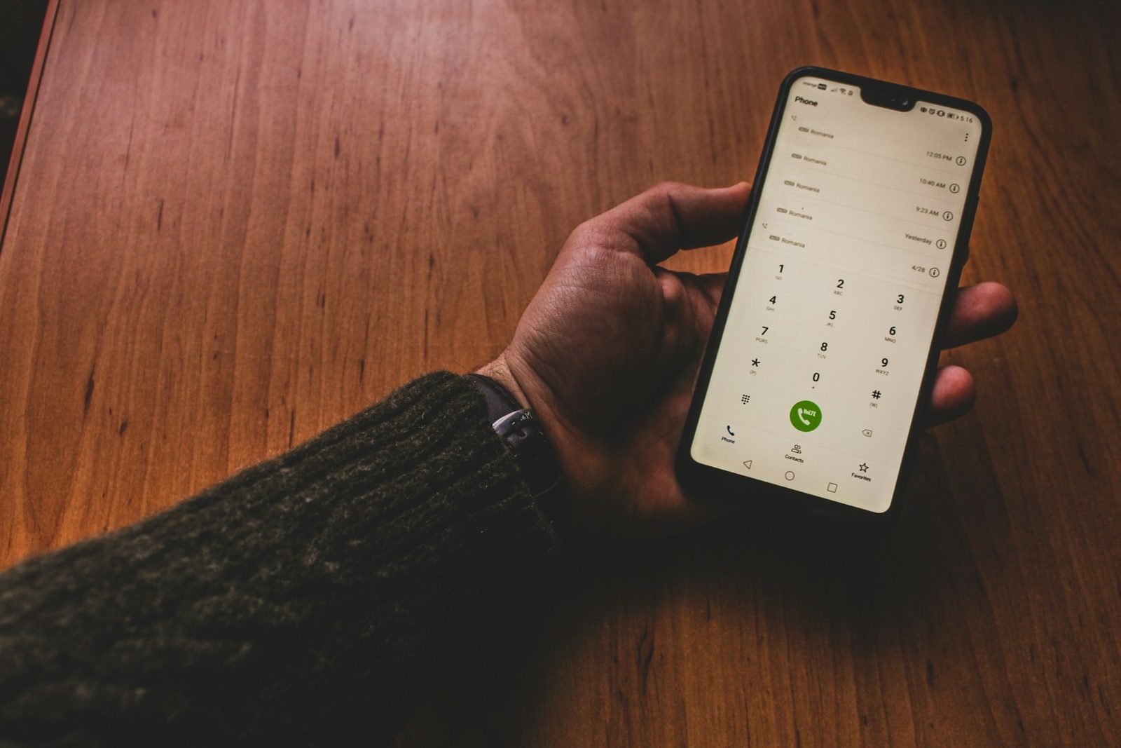Tangan memegang smartphone di layar panggilan